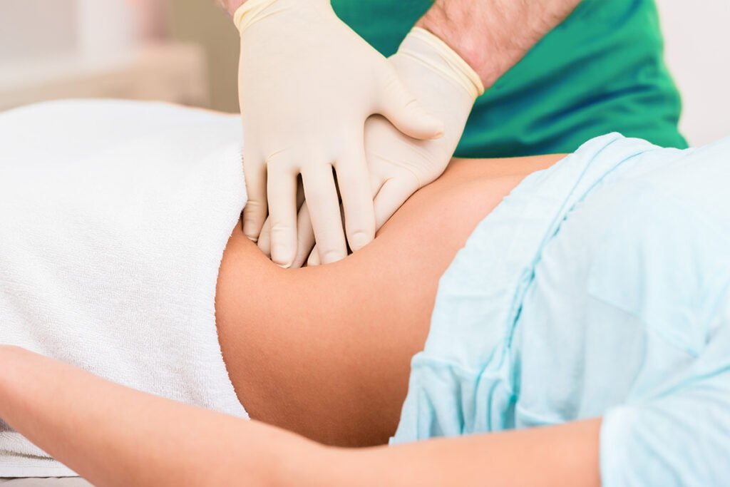 Practitioner at colon therapy massaging abdomen wall of woman